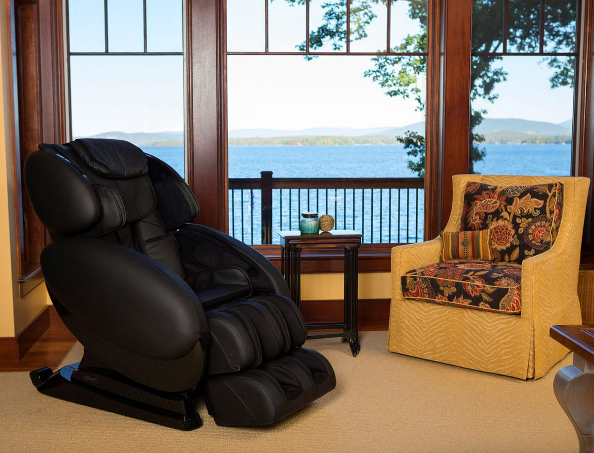Black massage chair in a room with large windows overlooking water