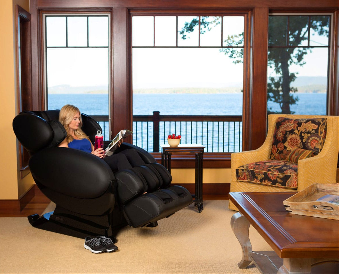 Woman sitting in a massage chair by a large window with a scenic view.